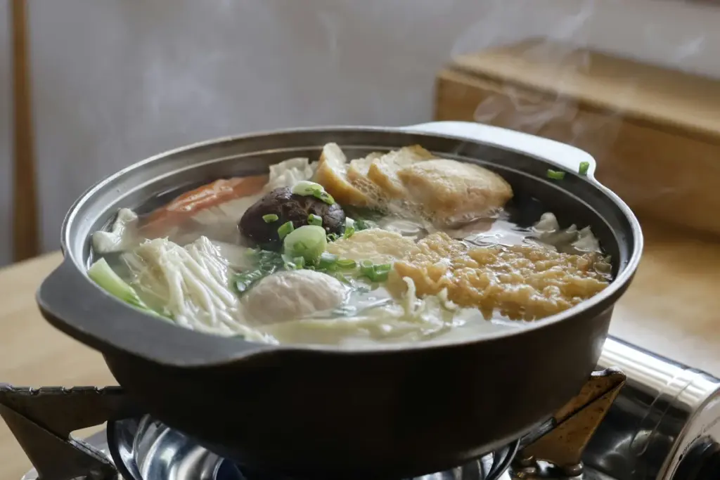 Nồi lẩu cá hồi nóng đầy nấm, rau và đồ nhúng trên bếp nhỏ ở Bếp Củi